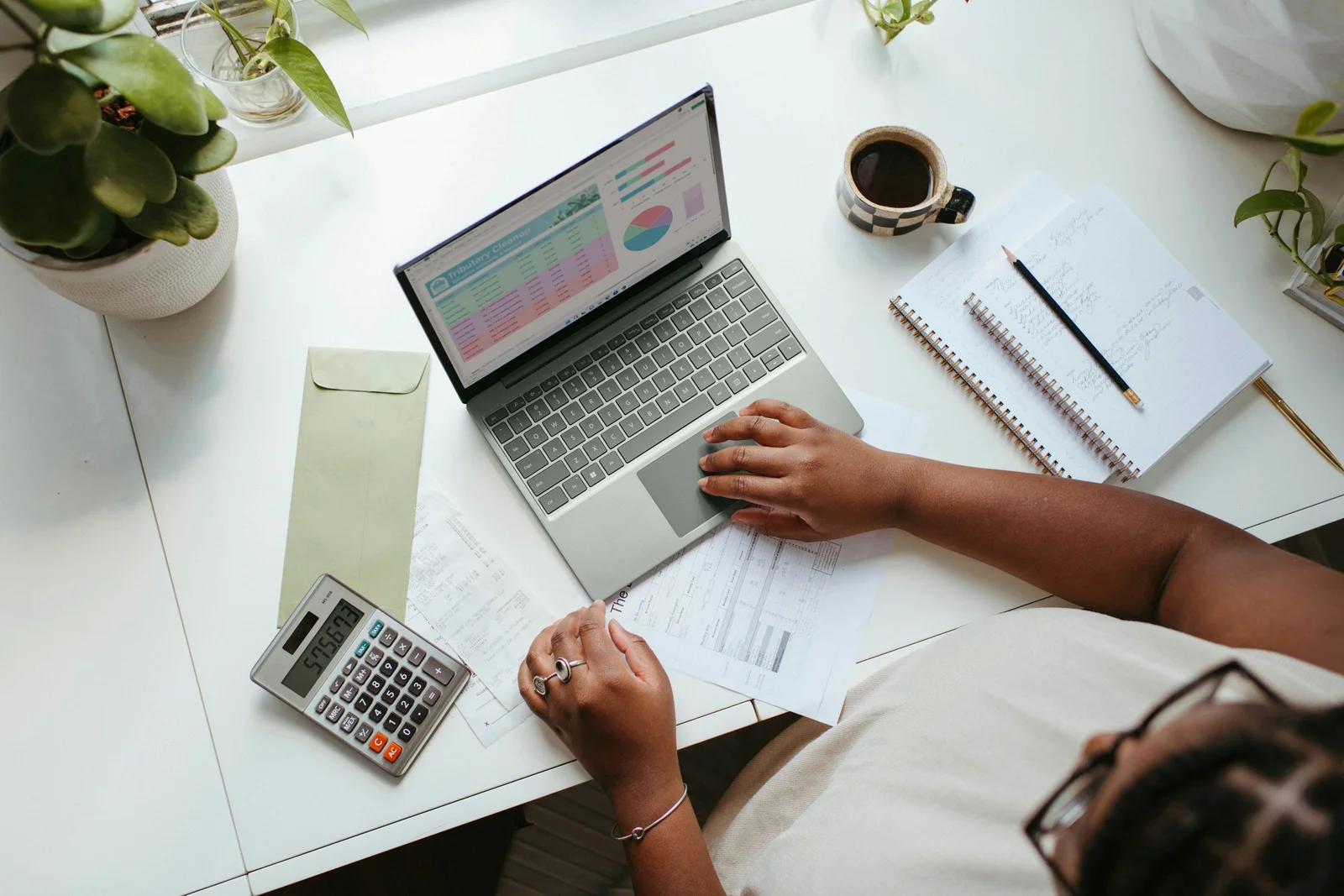 Secretária com computador portátil, calculadora e facturas